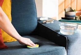 Person spot cleaning a stain on a couch with a cloth.