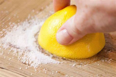 Natural cleaning solutions for wood cutting boards, including lemons, baking soda, vinegar, and salt.