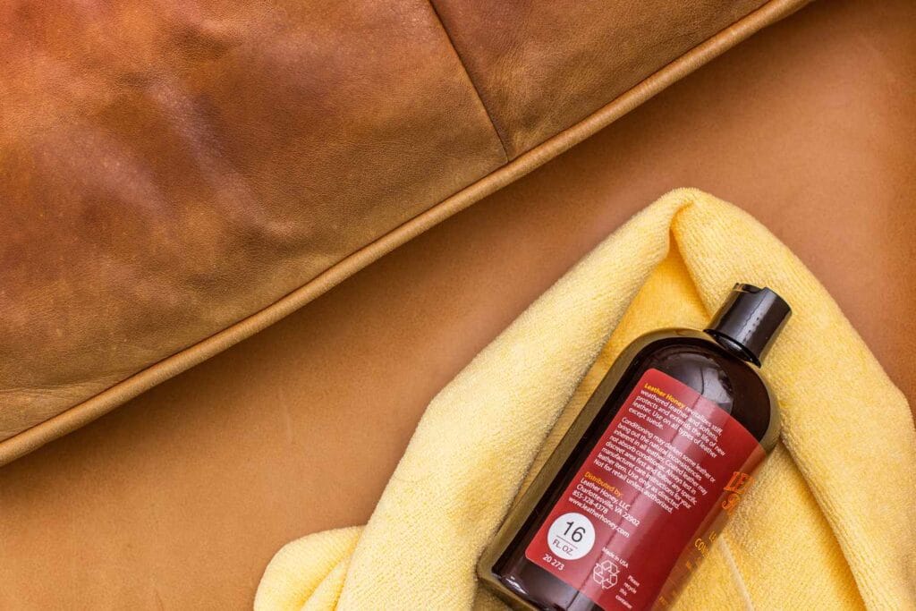 A variety of essential leather cleaning tools and products: a microfiber cloth, soft brush, leather cleaner, and conditioner.