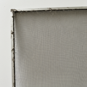 Dirty window screen leaned against outdoor wall