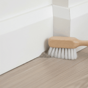 Using a brush for dust removal in baseboard corners